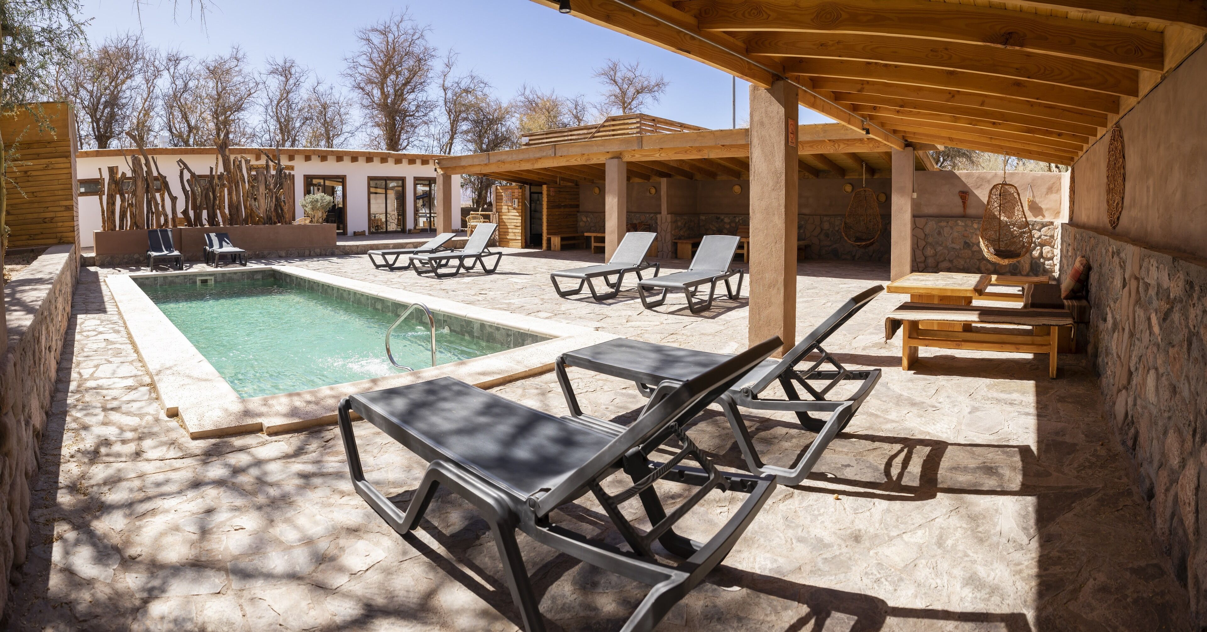 A pool area with lounge chairs and a covered seating area.