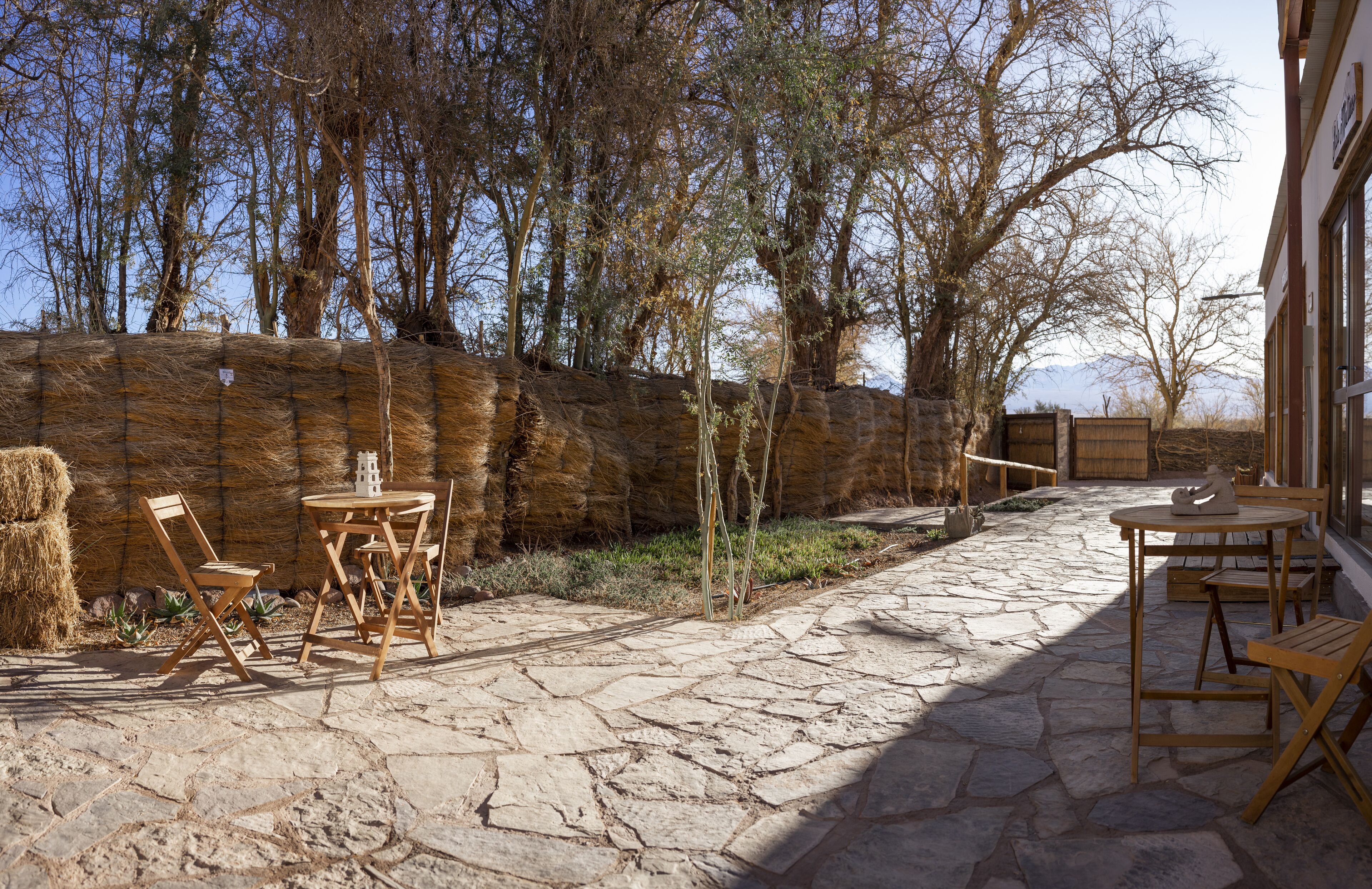 Un patio al aire libre con suelo de piedra, mobiliario de madera y un muro de piedra.