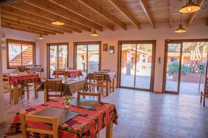 Un restaurante con mesas y sillas de madera, ventanas amplias y vistas al exterior.