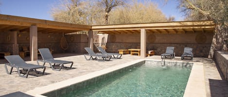 Una piscina al aire libre, sombrillas, sillones reclinables de piscina