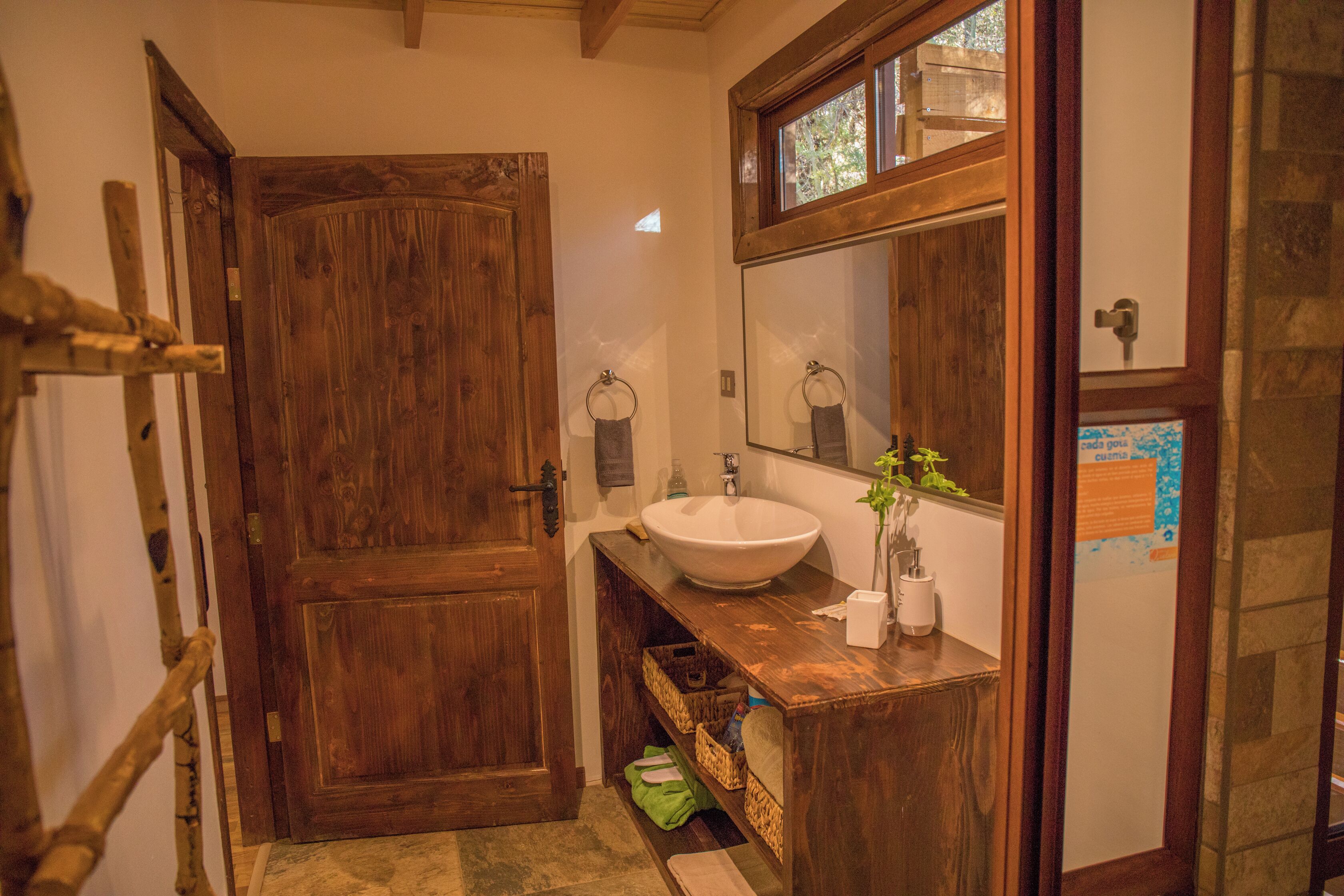A wooden bathroom with a large mirror, a sink, and a door.
