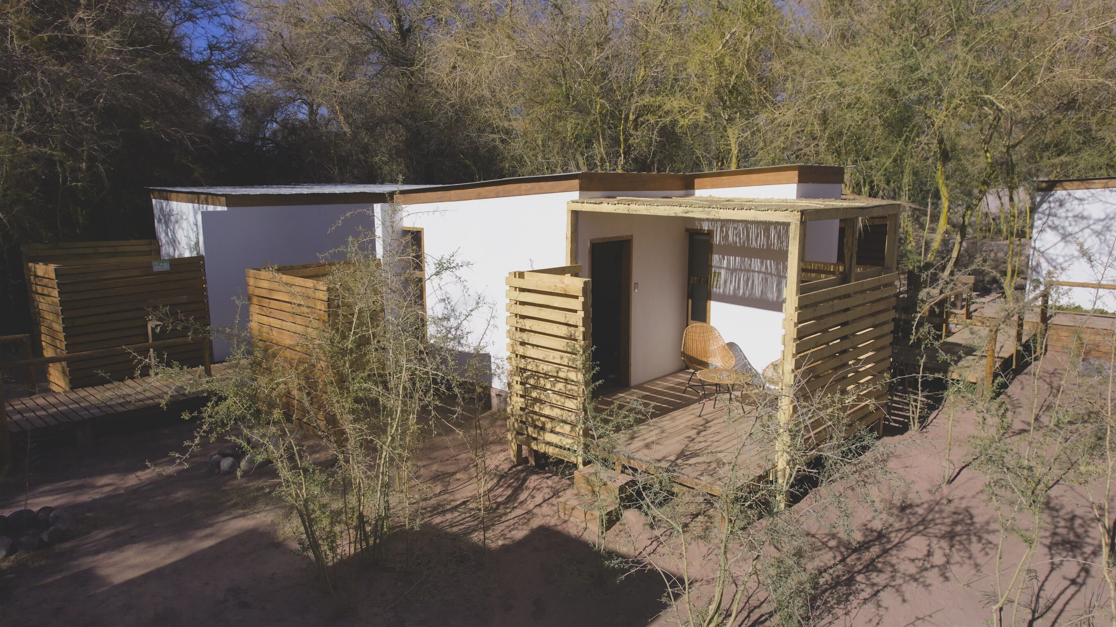 A series of small, wooden cabins with a simple, rustic design, surrounded by natural vegetation.