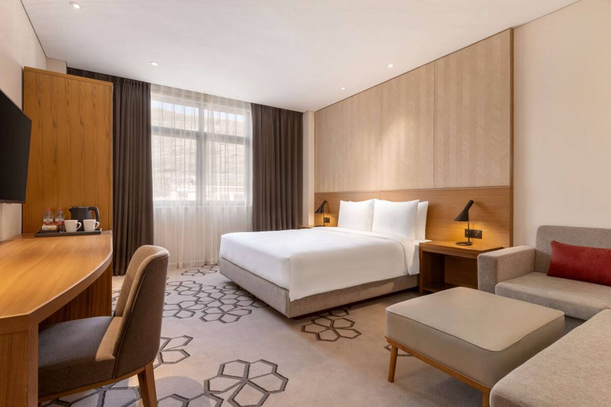 Una habitación de hotel moderna con una cama grande, un escritorio, un sofá y una mesita de centro.