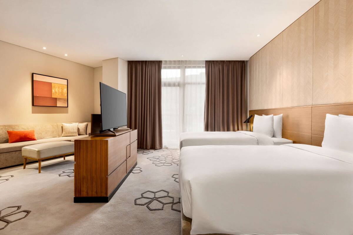 Una habitación de hotel con cama, sofá, televisor y escritorio.