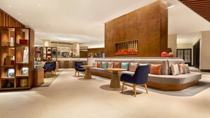 A modern lobby with a seating area, a wooden bookshelf, and a large wall with a decorative element. - Hyatt Place Chongli (Zhangjiakou)