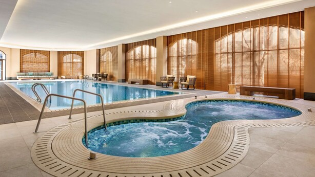 A large indoor swimming pool with a hot tub, surrounded by seating areas and large windows. - Hyatt Place Chongli (Zhangjiakou)
