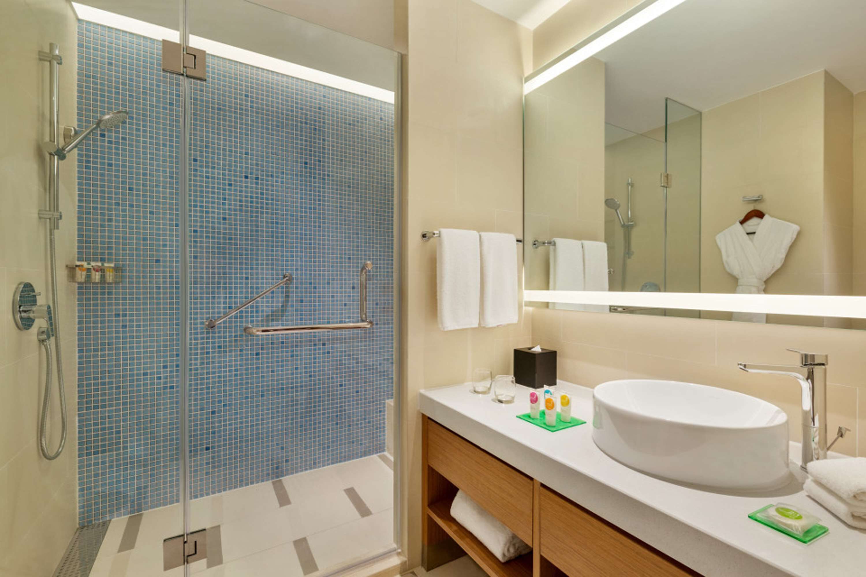 Une salle de bain moderne avec une douche à parois de verre, un lavabo blanc et un grand miroir.
