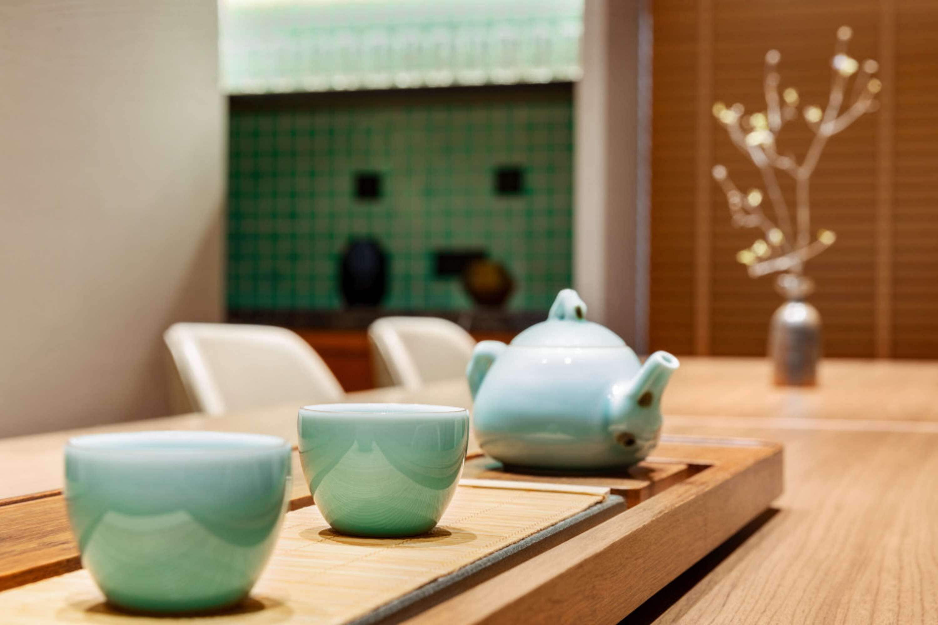 Une table en bois avec deux tasses en céramique et une théière.