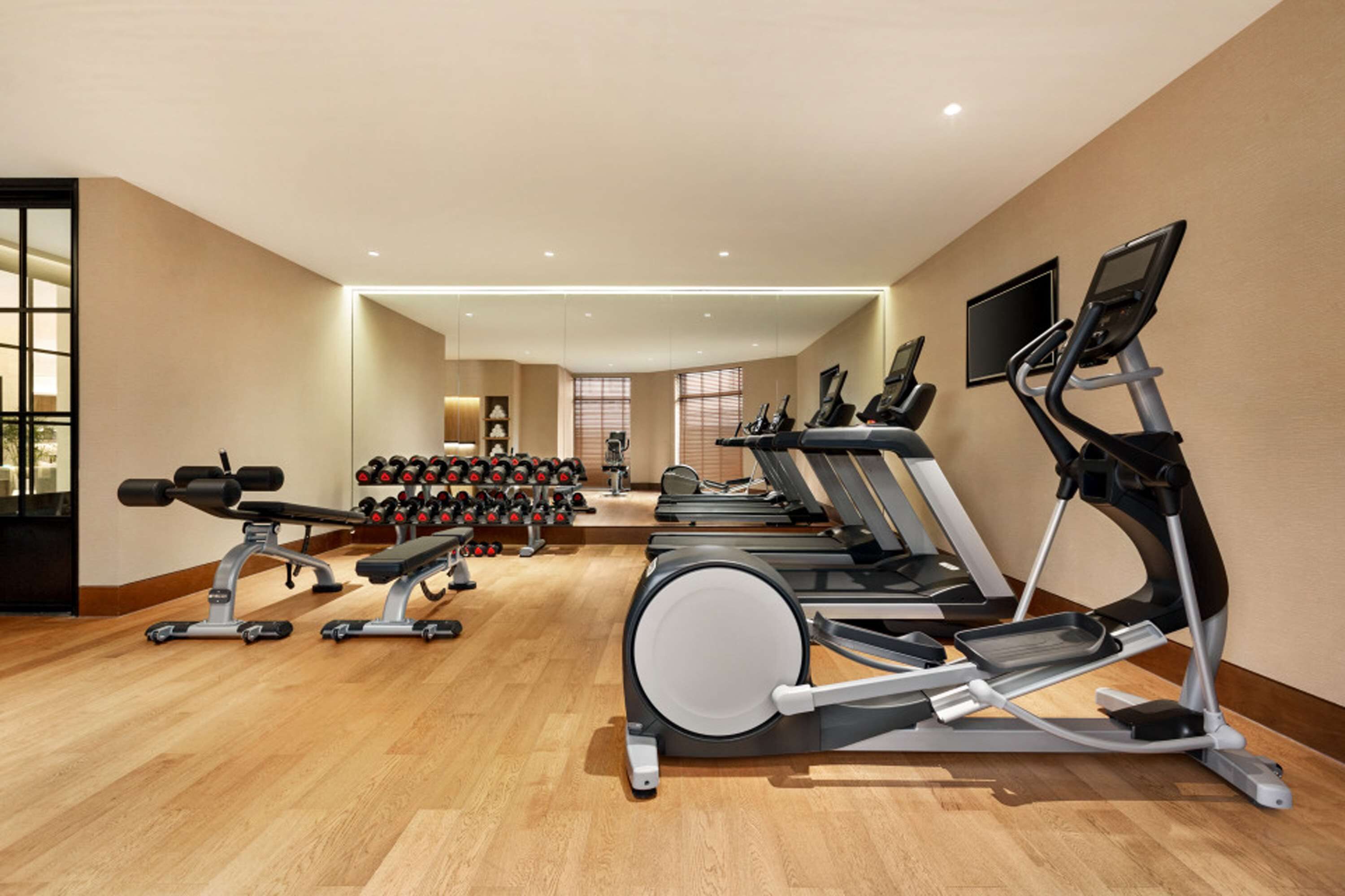 A gym with treadmills, elliptical machines, and a bench press.