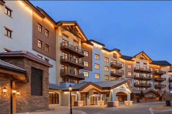 A multi-story hotel with balconies, a stone facade, and a well-lit entrance. - Hyatt Place Chongli (Zhangjiakou)
