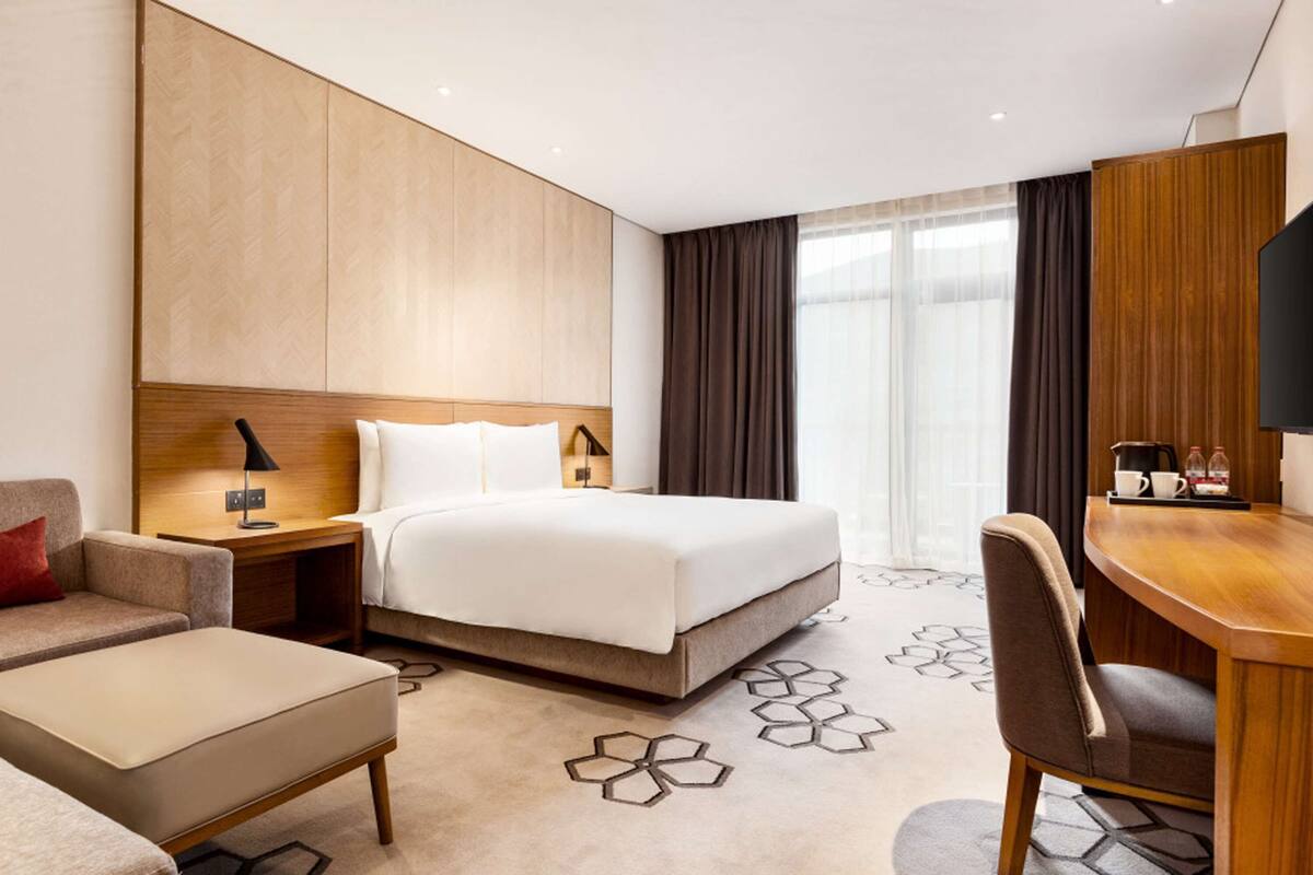 Una habitación de hotel moderna con una cama grande, un escritorio, una silla y un sofá.