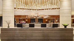 A reception area with a wooden reception desk, a large decorative umbrella sculpture, and hanging light fixtures. - Hyatt Place Chongli (Zhangjiakou)