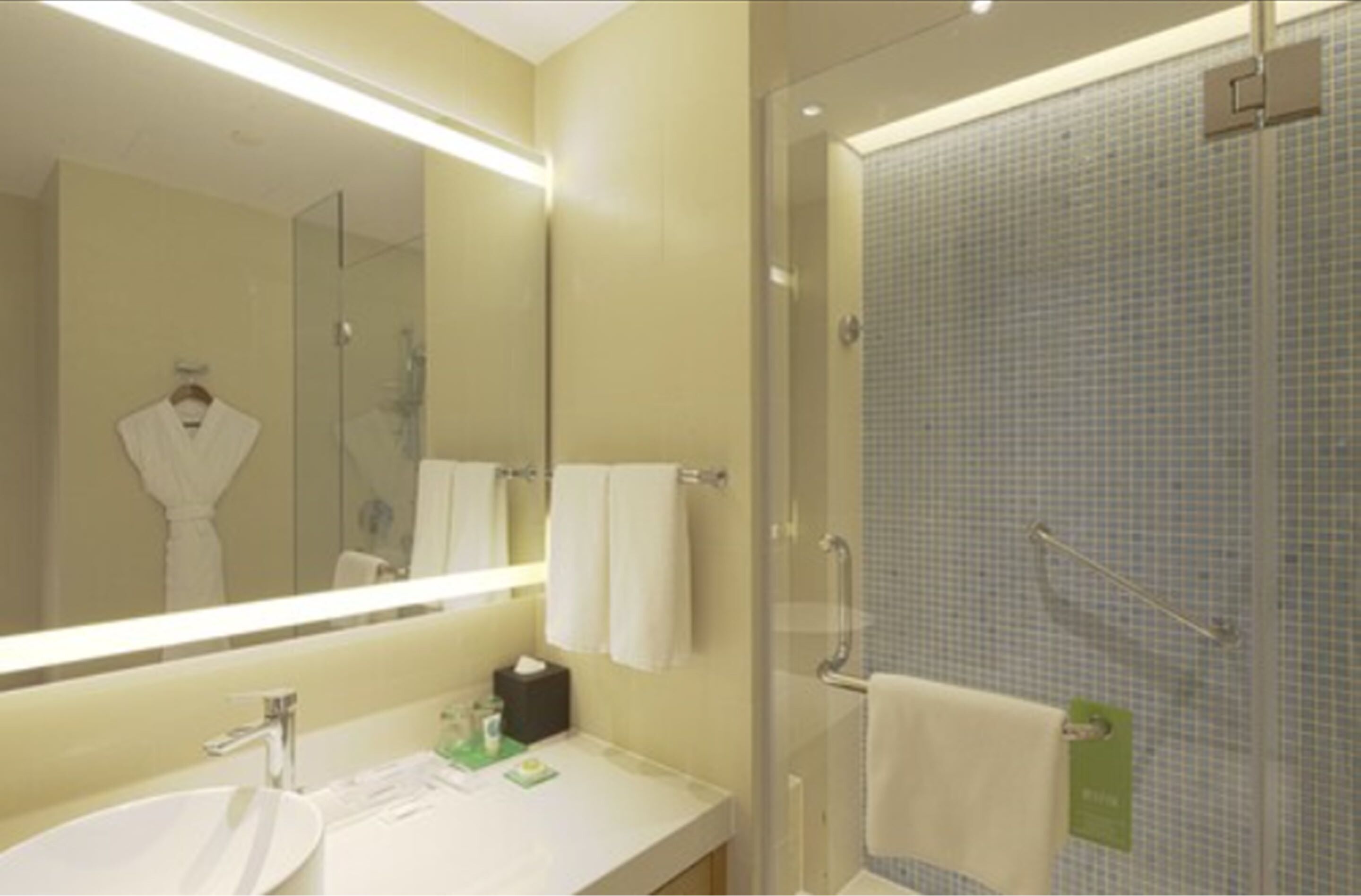 A modern bathroom with a large mirror, a sink, and a glass shower enclosure.