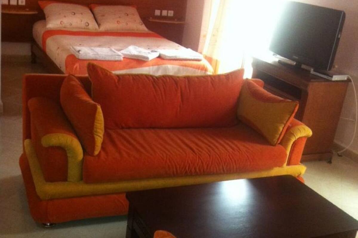 A hotel room with a bed, a sofa, a TV, and a small table.