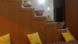 A room with a wooden staircase, a bed with yellow pillows, and a wall-mounted shelf with pottery. - Hôtel Oumaya Safa (Algiers)