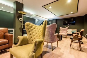 A modern living room with a tufted armchair, a round table, and a television mounted on the wall.