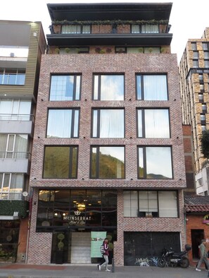 A multi-story hotel with a brick facade, large windows, and a visible entrance with a sign.