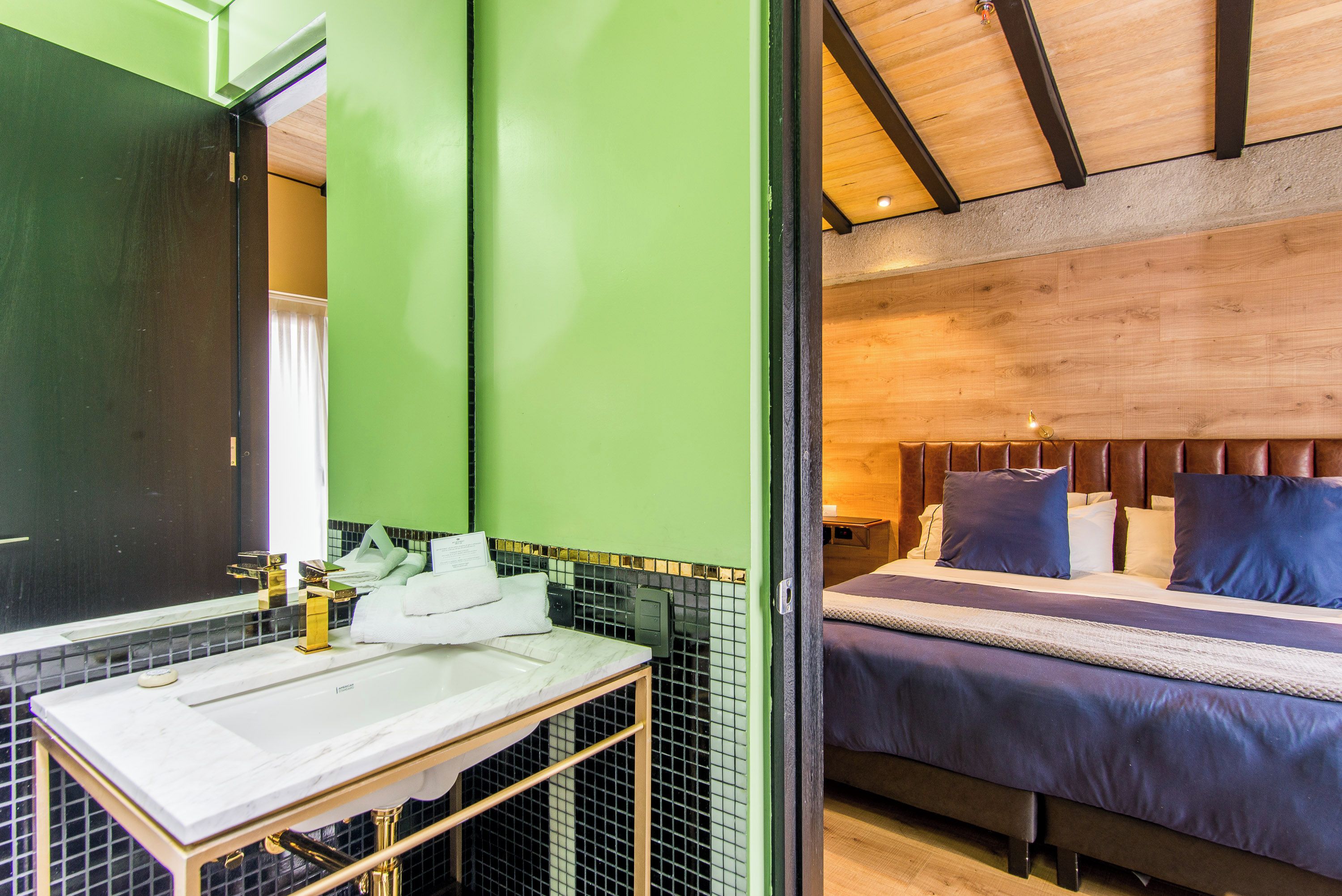 A bathroom with a white sink, green walls, and a wooden ceiling.