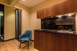 A modern kitchen with wooden cabinets, a black countertop, and a blue chair.