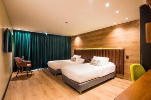 A modern hotel room with two beds, a wooden headboard, a desk, and a chair.
