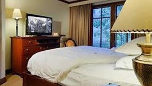 Une chambre d’hôtel avec un lit, une télévision, une lampe et une fenêtre avec des rideaux.