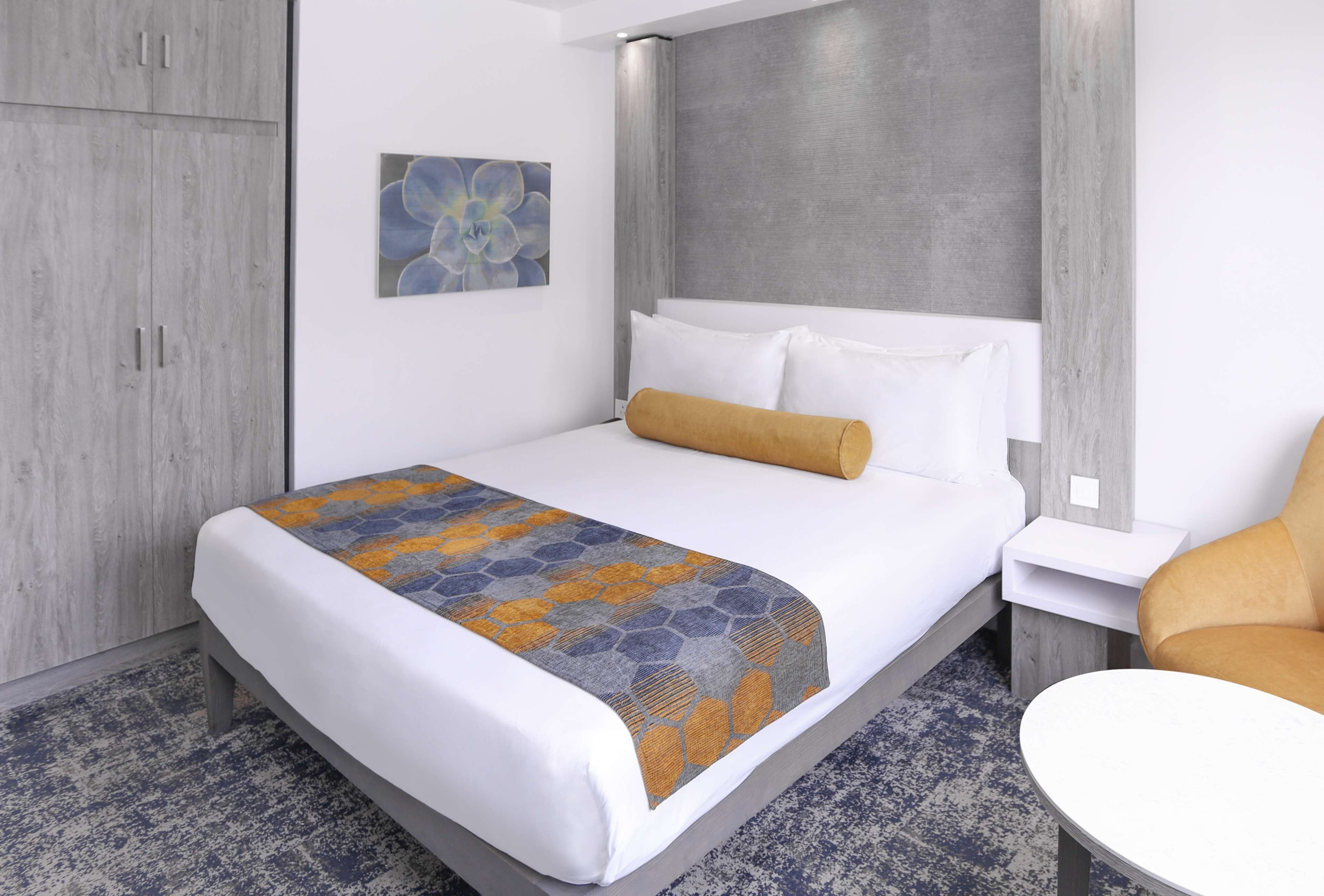 A hotel room with a bed, a nightstand, a chair, and a wardrobe.