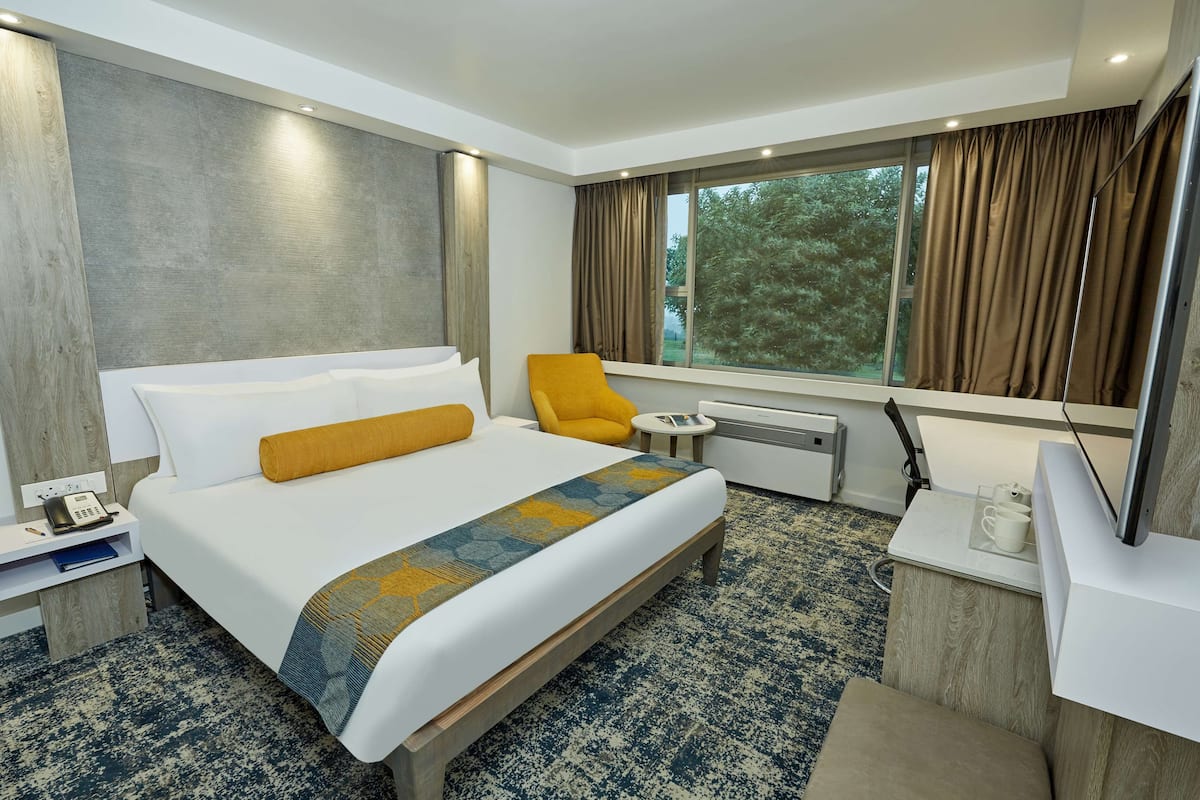 Een moderne hotelkamer met een groot bed, een bureau, een stoel en een raam met gordijnen.