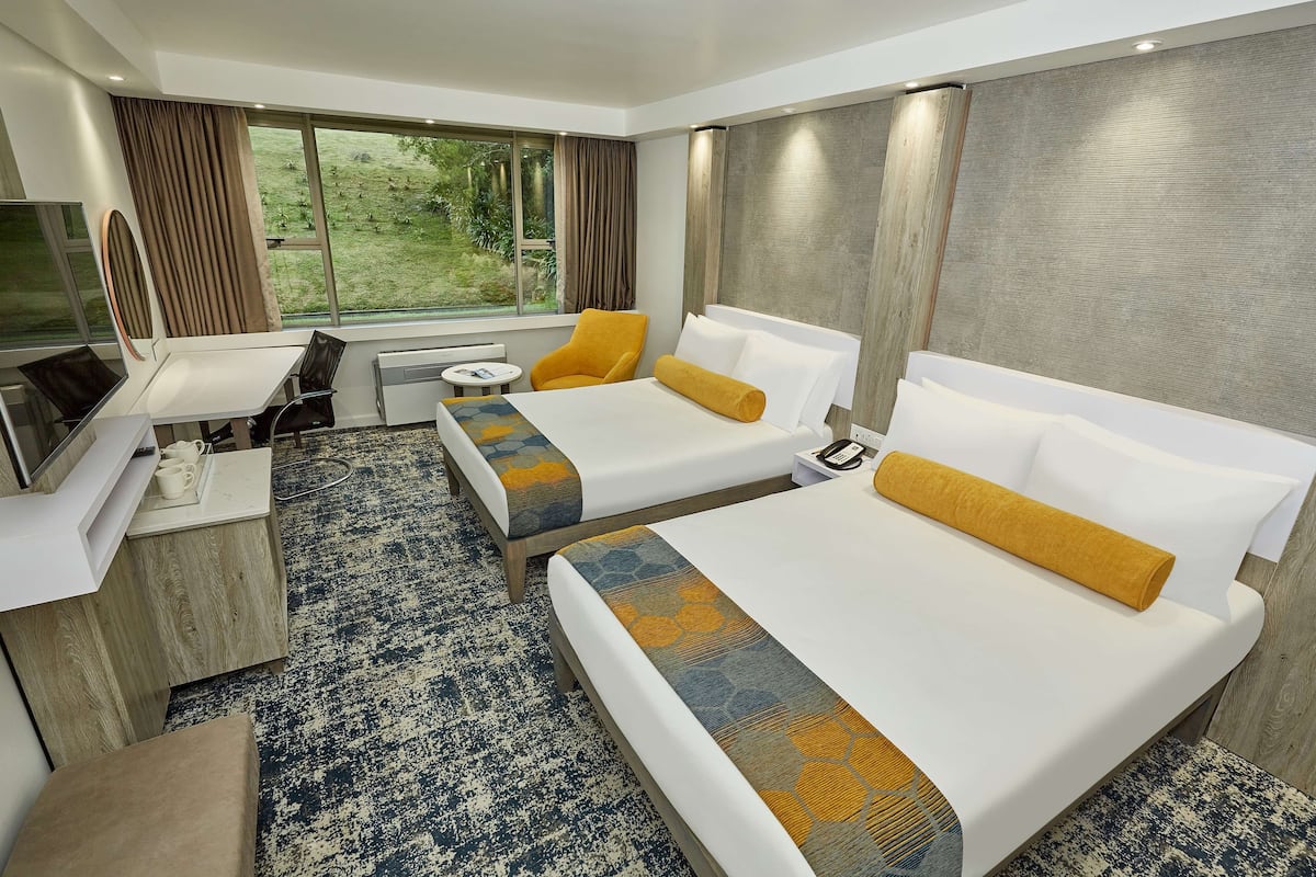 Een hotelkamer met twee bedden, een bureau, een stoel, een klein tafeltje en een televisie.