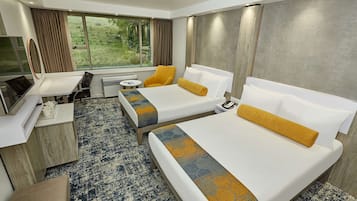 A hotel room with two beds, a desk, a chair, a small table, and a TV.