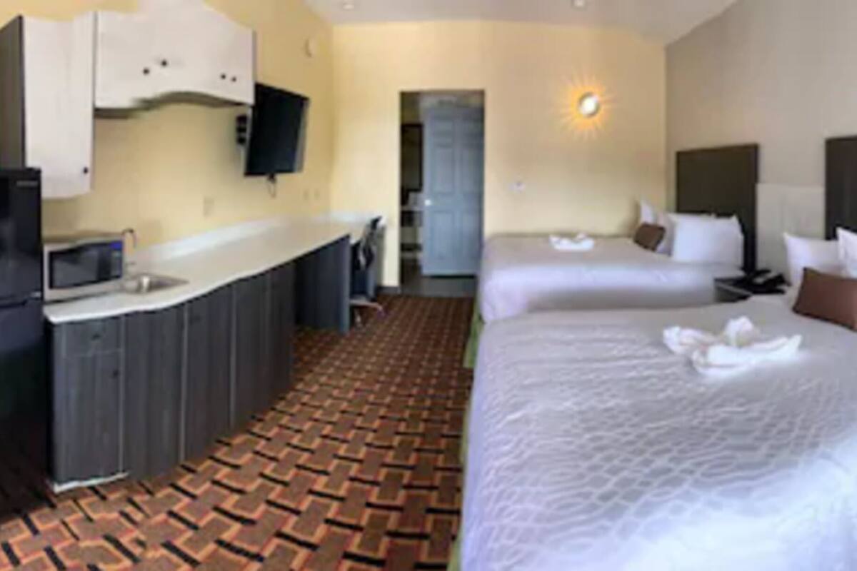 Habitación de hotel con kitchenette, dos camas y piso estampado.