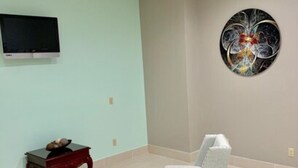 A room with two armchairs, a small table, a TV, and a decorative wall piece. - HomeStay Inn & Suites Edinburg (Edinburg)