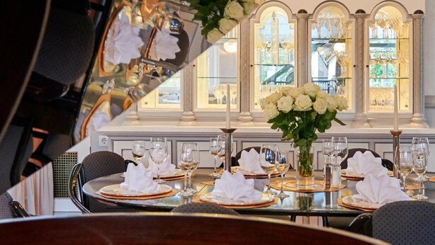 A dining table set with white napkins, glasses, and a vase of flowers. - Design Hotel Zur Abtei (Aachen)
