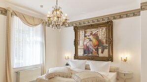 A bedroom with a large bed, a chandelier, a painting, and a nightstand. - Design Hotel Zur Abtei (Aachen)