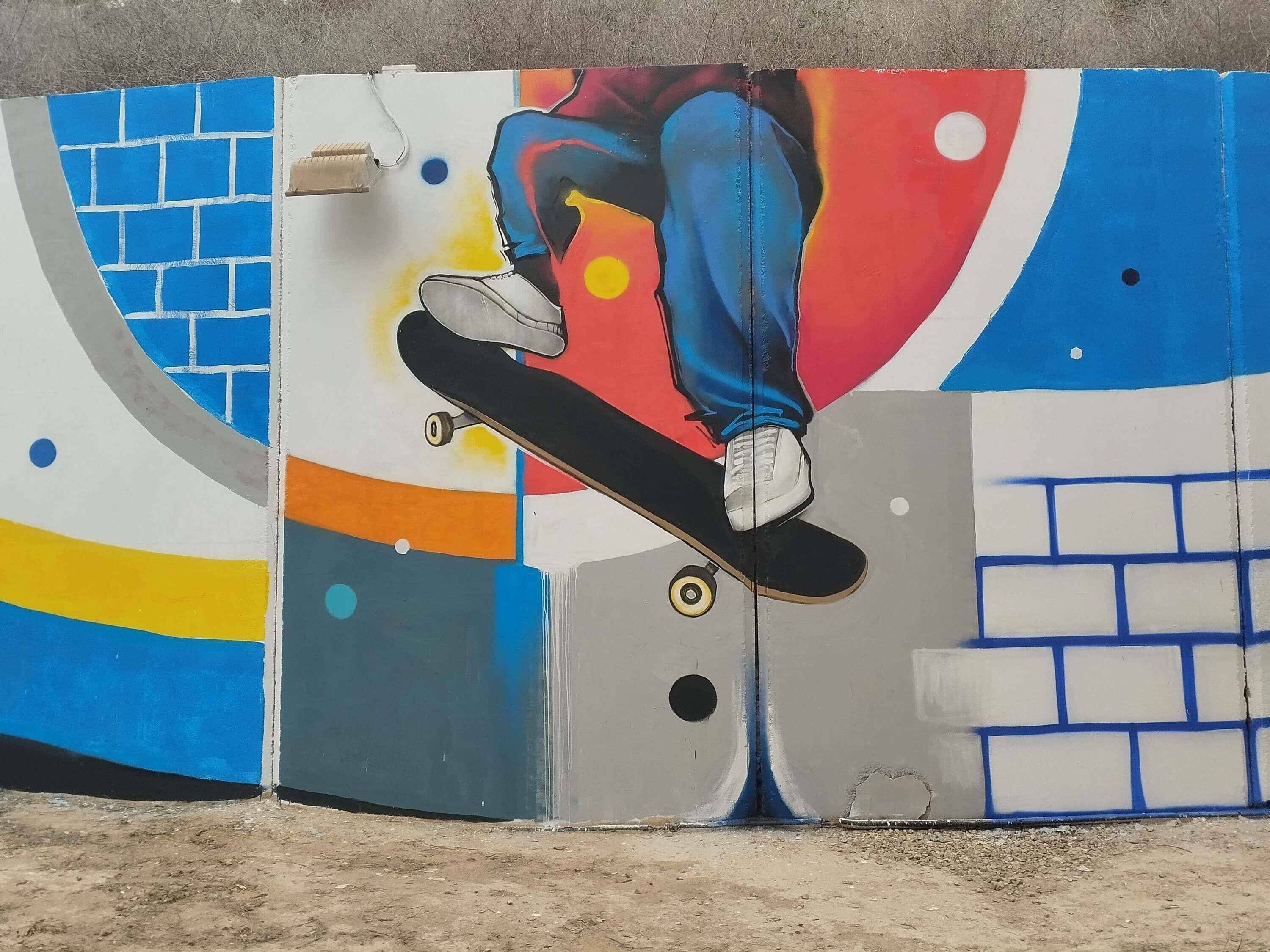 Una pared con un patinador realizando un truco, un diseño de ladrillos y formas abstractas.