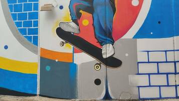 Una pared con un patinador realizando un truco, un diseño de ladrillos y formas abstractas.