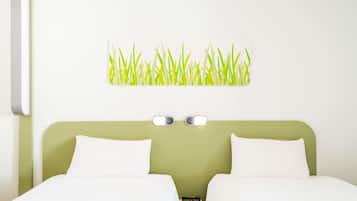 Habitación de hotel con cabecera verde, dos camas blancas, una lámpara de pared y un cuadro con motivos de hierba.