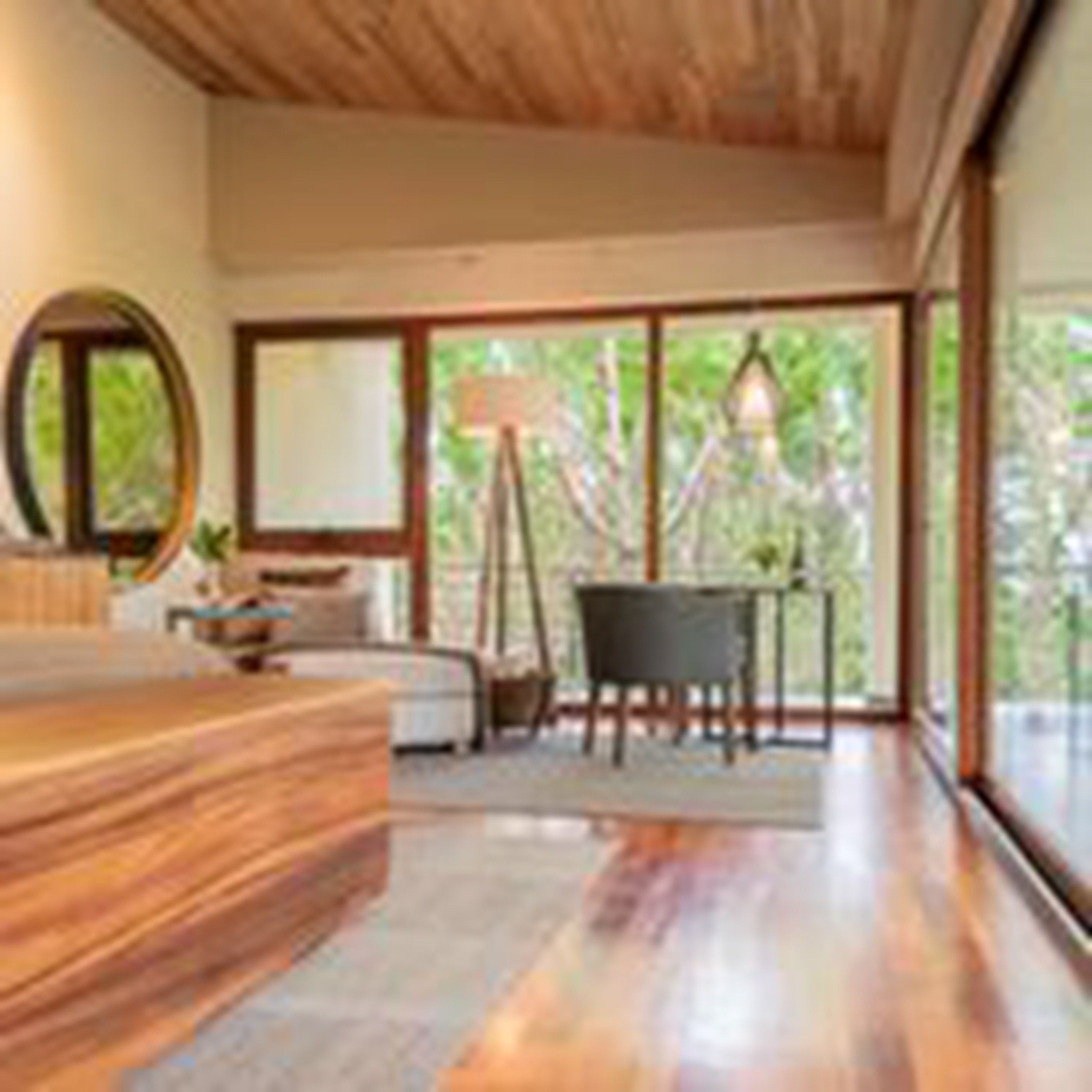 A modern bedroom with a wooden bed, a large window, and a view of greenery outside.