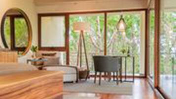 Une chambre moderne avec un lit en bois, une grande fenêtre et une vue sur la verdure environnante.