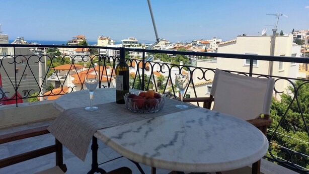 Ein Balkon mit Tisch, einer Flasche und einer Schüssel mit Obst.