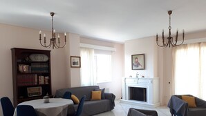 Ein Wohnzimmer mit Kamin, einem Esstisch mit Stühlen, einer Couch und einem Bücherregal.