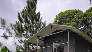 Ein modernes, zweistöckiges Haus mit überdachter Veranda, umgeben von üppiger Bepflanzung und einem gepflegten Rasen.