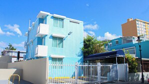 A blue building with white balconies, a white fence, and a street lamp. - Estudio con cocina, WiFi para trabajar remoto, cerca de la plaza de Ponce 301 (Ponce Pueblo)