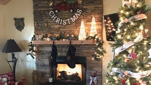 Un salon chaleureux avec une cheminée, un sapin de Noël et des décorations de fête.