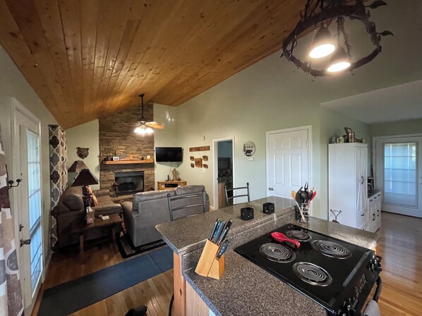 A modern kitchen with granite countertops, a black stove, and a dining area with a sofa and chairs. - Private Cabin Getaway- Long Range Mountain View’s! (Marble)