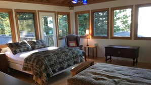 A bedroom with a bed, a chair, a nightstand, a dresser, and a window with a view of trees. - 8 Miles Of Sand Beach To Explore ~ Outstanding Sunrise Views Over The Lake! (Sturgeon Bay)