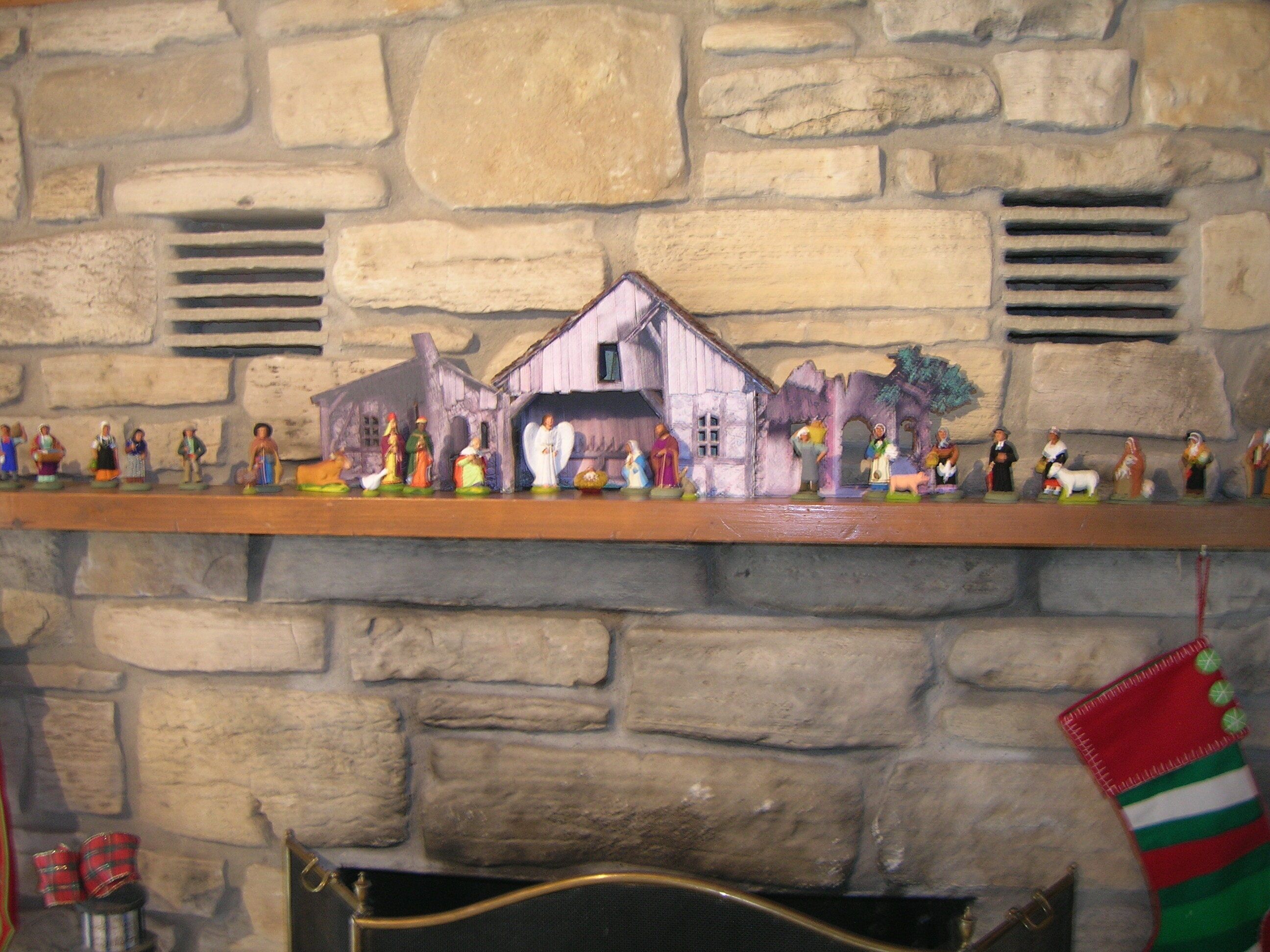 A stone fireplace with a mantel displaying figurines and a Christmas stocking.