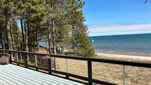 A wooden deck with a railing overlooking a beach and a forest. - 8 Miles Of Sand Beach To Explore ~ Outstanding Sunrise Views Over The Lake! (Sturgeon Bay)