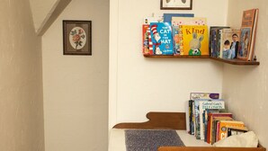 A bedroom with a bed, a wooden headboard, a shelf with books, and a framed picture on the wall. -  Cottage by the lake (Raymond Island)