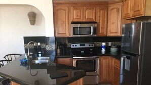 A kitchen with wooden cabinets, a stainless steel refrigerator, a microwave, an oven, and a sink. - Pet Friendly! Beach Bungalow, Peaceful, Private, 2 Bedroom, 2 Bath. (Puerto Penasco)