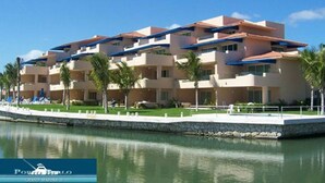 Un hotel de varios pisos con balcones, piscina y palmeras.